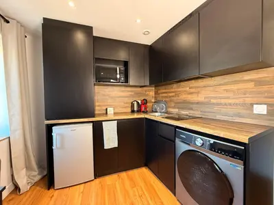 a kitchen with black cabinets and a washer and dryer at Le Baroque Studio Wifi in Narbonne