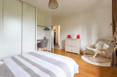 a bedroom with a bed and a chair at L'Écrin de Pamiers - Appt climatisé pour 6 in Pamiers