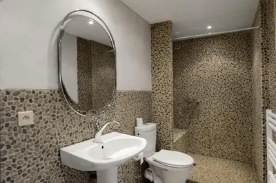 a bathroom with a sink and a toilet and a mirror at Le Clos Saint Jean, vue Cité, piscine et parking in Carcassonne
