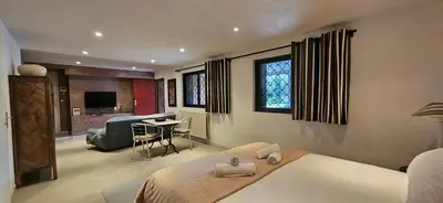 a bedroom with a bed and a living room at Le Clos Saint Jean, vue Cité, piscine et parking in Carcassonne