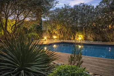 a swimming pool in a garden at night at Le Clos Saint Jean, vue Cité, piscine et parking in Carcassonne