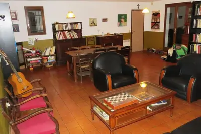 a living room with chairs and a table and a guitar at Maison 90m2 avec grand parc au bord de la rivière in Montredon-Labessonnié