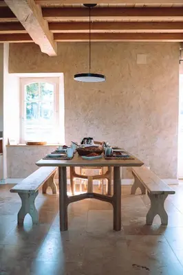 a table in a room with two benches and a ceiling at Chambre tout confort à l'Héritier - au coeur du Tarn in Marzens