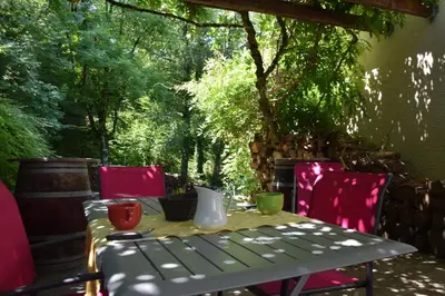 a table and chairs on a patio with trees at Chambres d'Hôtes L'Orée des Bois in Lacrouzette
