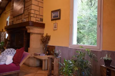 a living room with a fireplace and a chair at Chambres d'Hôtes L'Orée des Bois in Lacrouzette