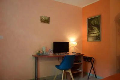 a room with a desk with a computer and a blue chair at Chambres d'Hôtes L'Orée des Bois in Lacrouzette