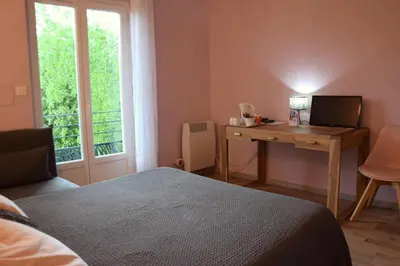 a bedroom with a bed and a desk with a computer at Chambres d'Hôtes L'Orée des Bois in Lacrouzette