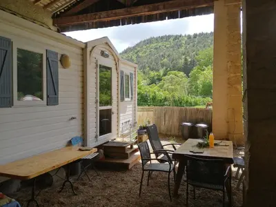 a patio with a table and chairs and a house at Mobilhome Ferme équestre La Mouillère in Chalabre