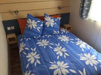 a bed with blue and white sheets and pillows at Mobilhome Ferme équestre La Mouillère in Chalabre