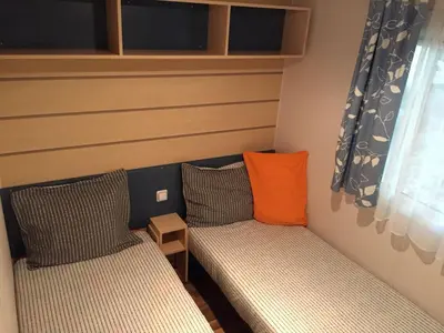 a small room with two beds and an orange pillow at Mobilhome Ferme équestre La Mouillère in Chalabre