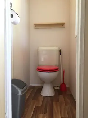 a bathroom with a toilet with a red lid at Mobilhome Ferme équestre La Mouillère in Chalabre