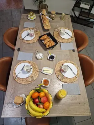 a kitchen with a wooden table with chairs and a window at L'escapade colorée anciennement La Vieille Forge in Rieux-Minervois