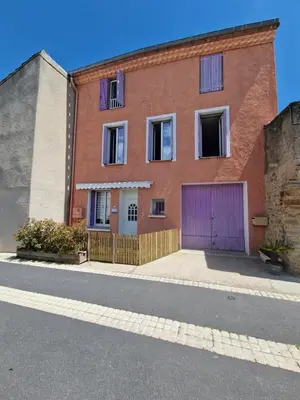 a patio with a pink table and chairs and a kitchen at L'escapade colorée anciennement La Vieille Forge in Rieux-Minervois