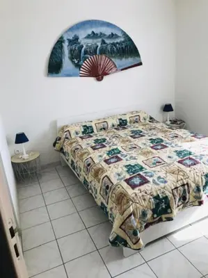 a bedroom with a bed with a quilt on it at Maison 6 personnes plage à 5min in Port-la-Nouvelle