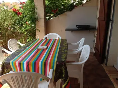 a table with white chairs and a colorful table cloth at Maison 6 personnes plage à 5min in Port-la-Nouvelle