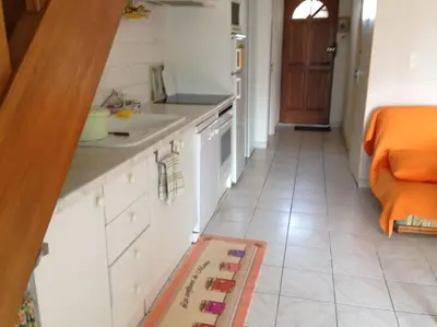 a kitchen with white cabinets and an orange bed at Maison 6 personnes plage à 5min in Port-la-Nouvelle