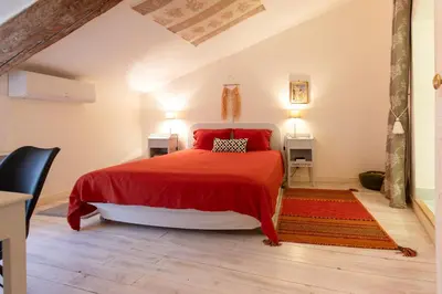 a bedroom with a red bed with a red blanket at Le Segarius superbe maison médiévale Internet WiFi gratuit Climatisation Jardin in Puisserguier