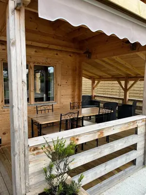 a wooden pavilion with tables and chairs on a porch at Chalet détente in Montaut