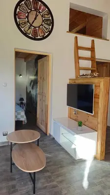 a living room with a tv and a clock on the wall at Chalet détente in Montaut