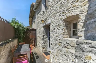 a stone house with a table and chairs outside at Les Bellevue Cité Trivalle 