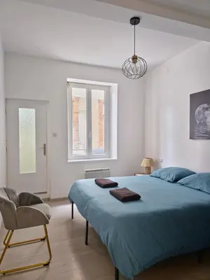 a bedroom with a large blue bed and a chair at Tour Ouest - T2 entre Cité Médiévale et Bastide in Carcassonne