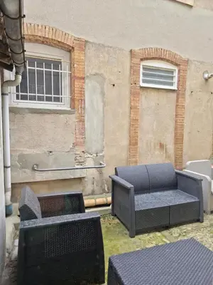 a patio with chairs and a couch in front of a building at Tour Ouest - T2 entre Cité Médiévale et Bastide in Carcassonne