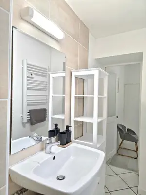 a white bathroom with a sink and a mirror at Tour Est - T2 entre Cité Médiévale et Bastide in Carcassonne