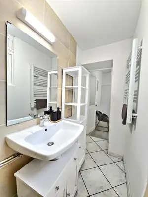 a white bathroom with a sink and a mirror at Tour Est - T2 entre Cité Médiévale et Bastide in Carcassonne