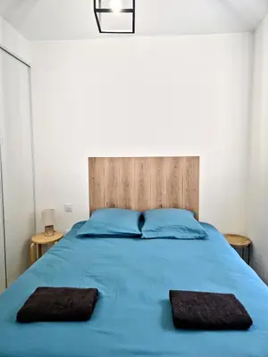 a bedroom with a blue bed with two pillows at Tour Est - T2 entre Cité Médiévale et Bastide in Carcassonne