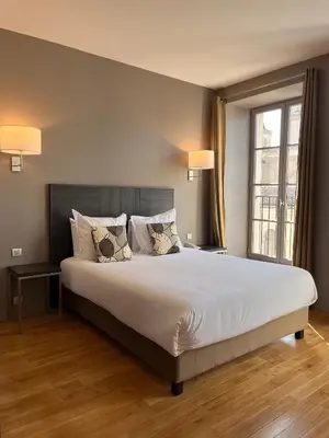 a bedroom with a large bed and a large window at Grand Hotel de Castres in Castres
