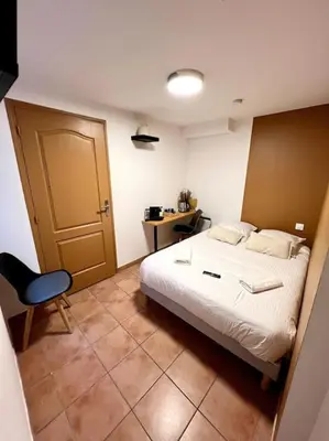 a bedroom with a bed and a chair and a door at Les chambres de la bastide - 201 in Carcassonne