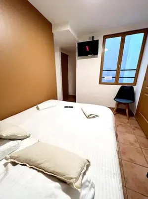 a bedroom with a bed with white sheets and a window at Les chambres de la bastide - 201 in Carcassonne