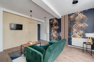 a living room with a green couch and a tv at Cocon de la Place in Villefranche-de-Lauragais