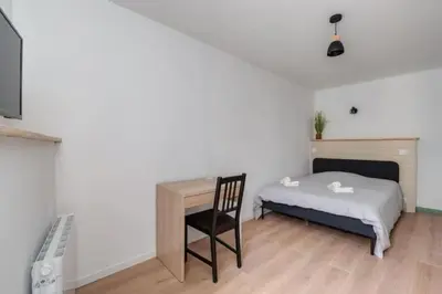 a bedroom with a bed and a desk and a chair at Cocon de la Place in Villefranche-de-Lauragais