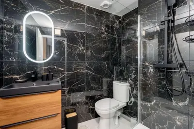 a black tiled bathroom with a toilet and a sink at Cocon de la Place in Villefranche-de-Lauragais