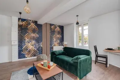 a living room with a green couch and a table at Cocon de la Place in Villefranche-de-Lauragais