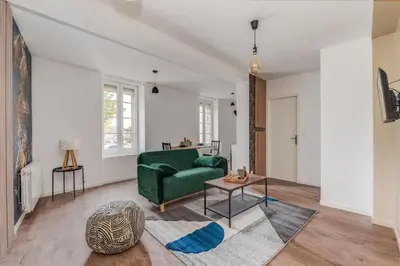 a living room with a green couch and a table at Cocon de la Place in Villefranche-de-Lauragais