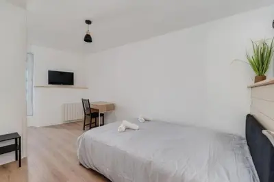 a white bedroom with a bed and a table at Cocon de la Place in Villefranche-de-Lauragais