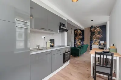 a kitchen with white cabinets and a dining room at Cocon de la Place in Villefranche-de-Lauragais