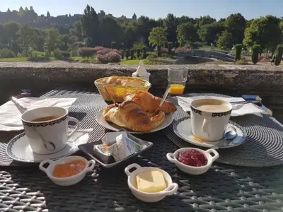 a table with two cups of coffee and a plate of food at Carcassonne Guesthouse in Carcassonne