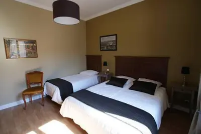 a hotel room with two beds and a chair at Carcassonne Guesthouse in Carcassonne
