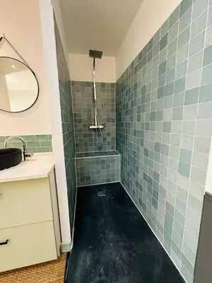 a bathroom with a sink and a shower with green tiles at Ancien chai rénové avec piscine in Paraza
