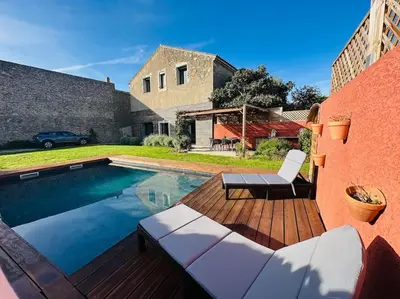 a backyard with a swimming pool and a wooden deck at Ancien chai rénové avec piscine in Paraza