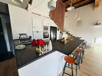 a kitchen with a black counter top with stools at Ancien chai rénové avec piscine in Paraza