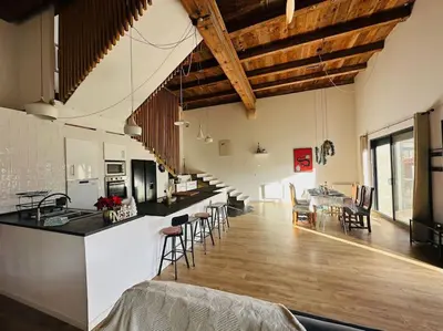 a kitchen and living room with a table and chairs at Ancien chai rénové avec piscine in Paraza