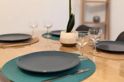 a wooden table with plates and wine glasses on it at Spacieux T2 au centre ville avec parking et climatisation in Carcassonne