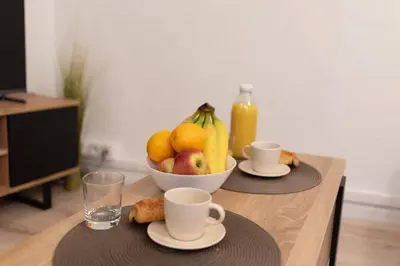 a table with a bowl of fruit and two cups at Spacieux T2 au centre ville avec parking et climatisation in Carcassonne