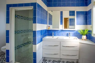 a blue tiled bathroom with a shower and a sink at Villa Loupia by Villa Plus in Loupia