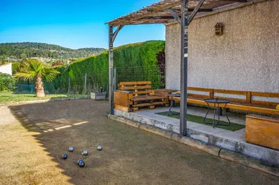a patio with benches and a table and balls on the ground at Villa Loupia by Villa Plus in Loupia