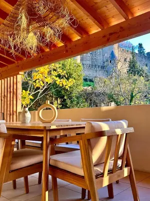 a wooden table and chairs on a porch with a window at Maison Henriette - Au plus près de la Cité Médiévale in Carcassonne